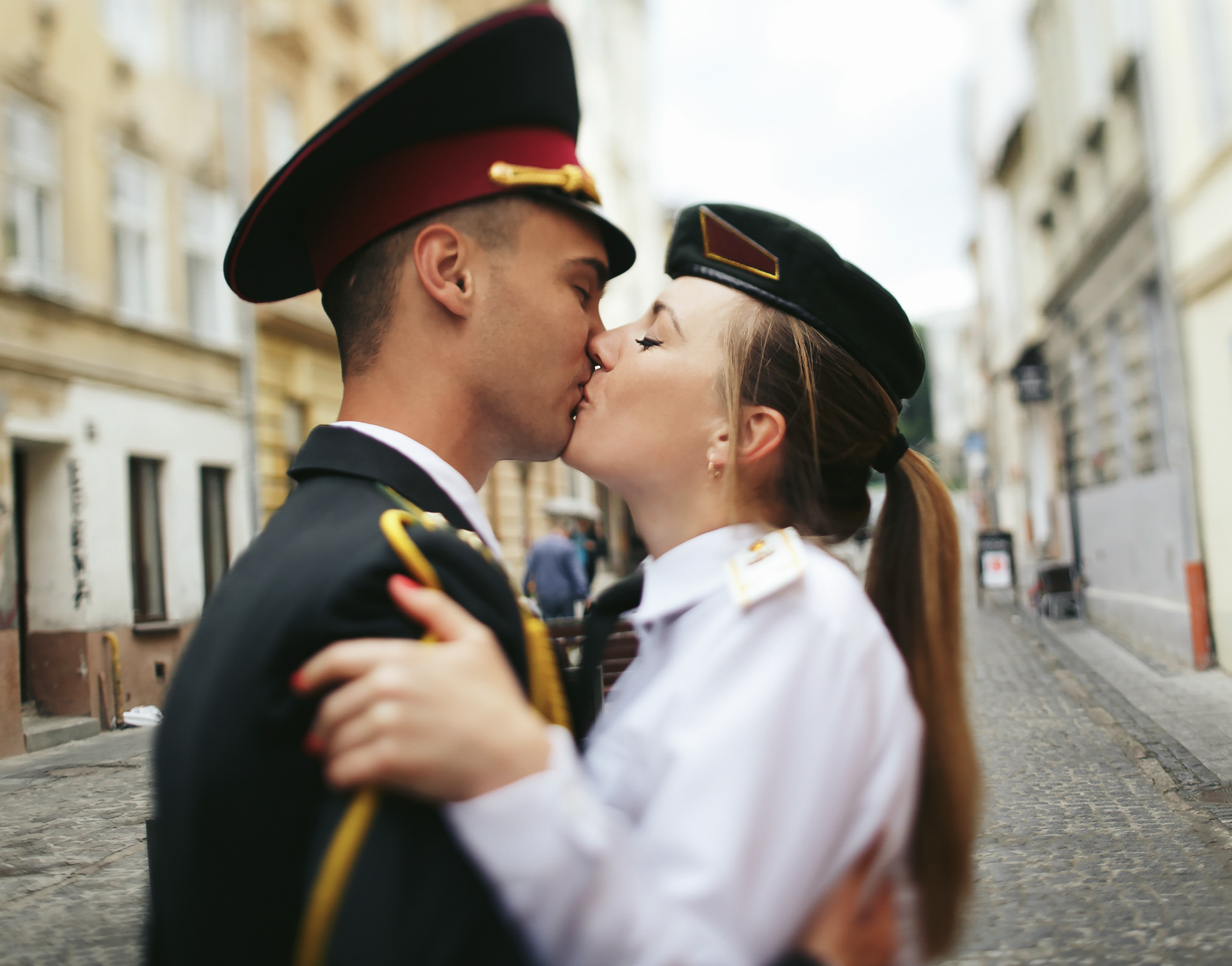 Pilot couple kissing in uniform on a city street