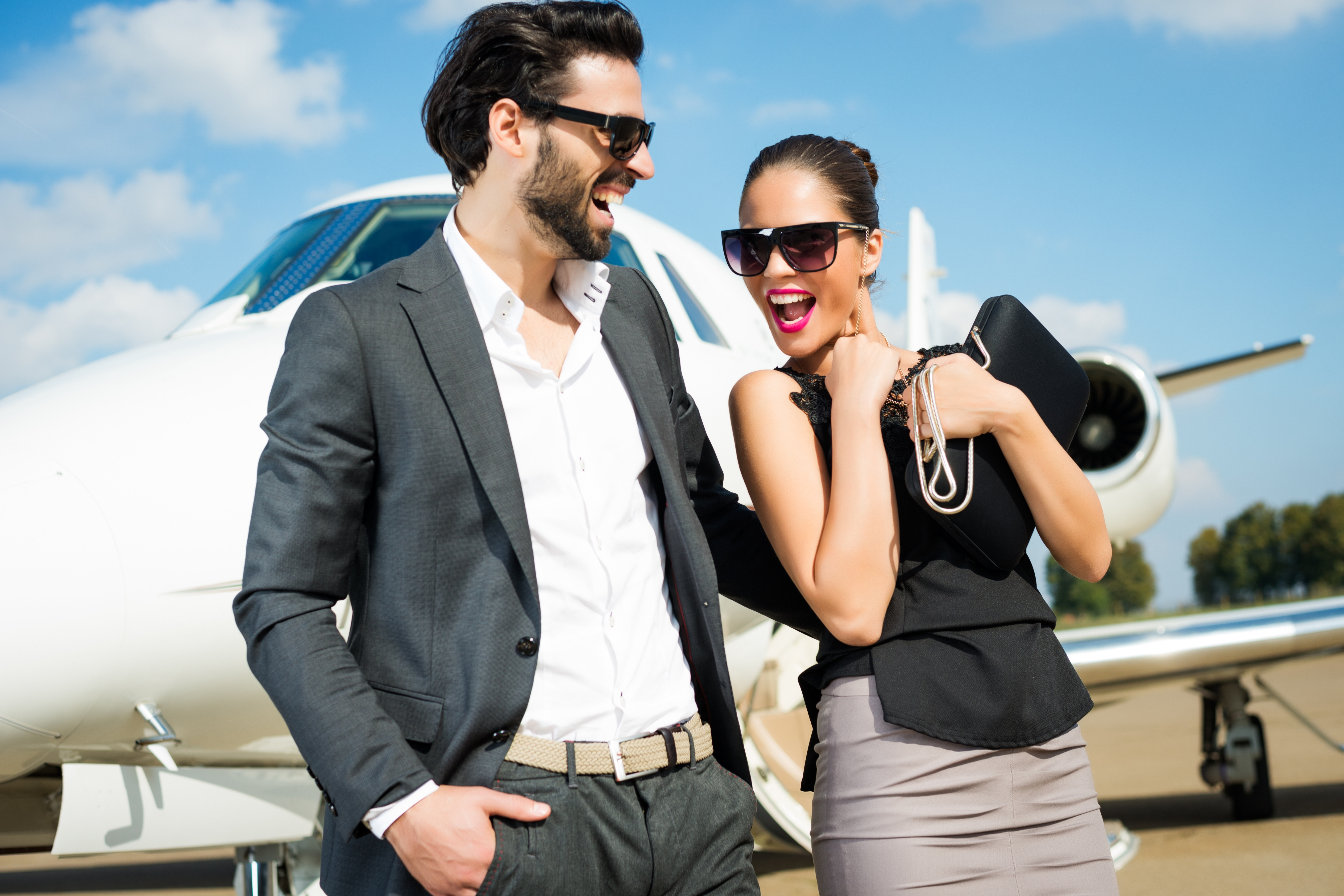 Elegant couple laughing beside a private jet